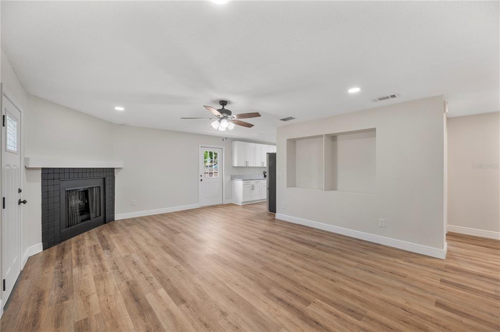 A living room features wood-look flooring, a corner fireplace, and a built-in wall niche — 1215 EL CAMINO ROAD, LAKELAND, FL