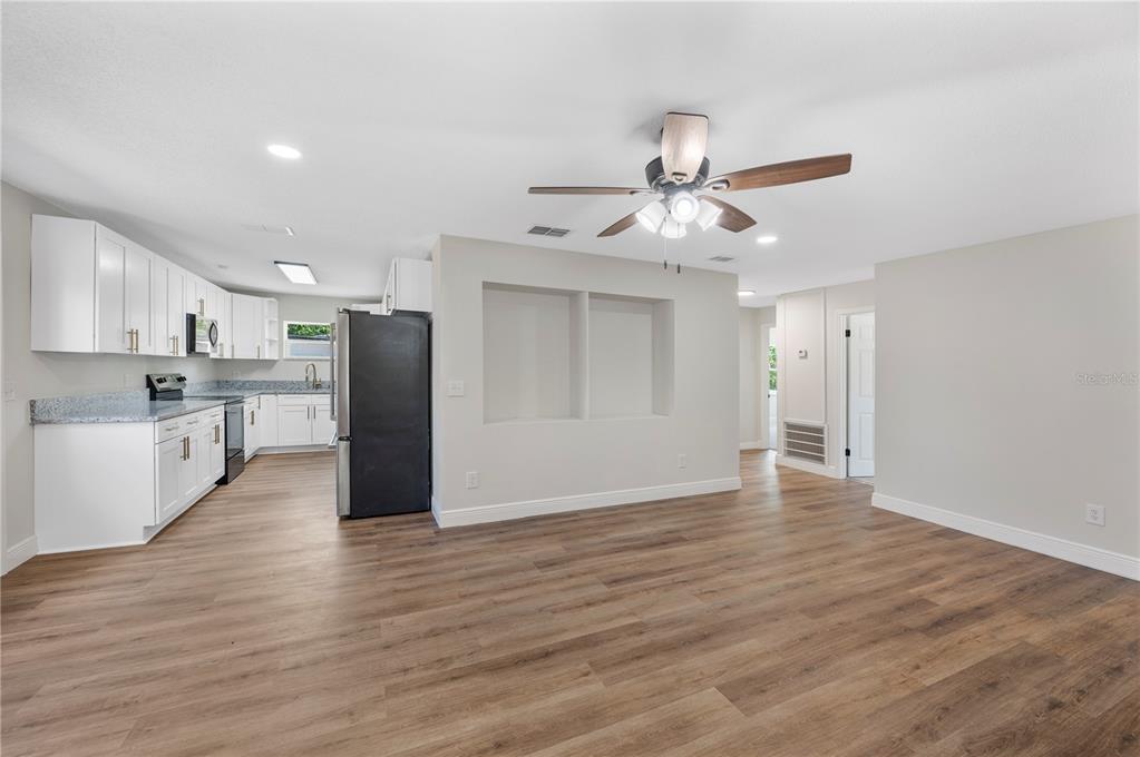A kitchen with white cabinets and a living area featuring wood-look flooring and recessed niches — 1215 EL CAMINO ROAD, LAKELAND, FL