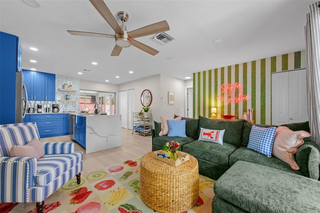 A living room with a green sofa, blue kitchen cabinets, and a fruit-patterned area rug — 7957 COTTONWOODE DRIVE, LARGO, FL