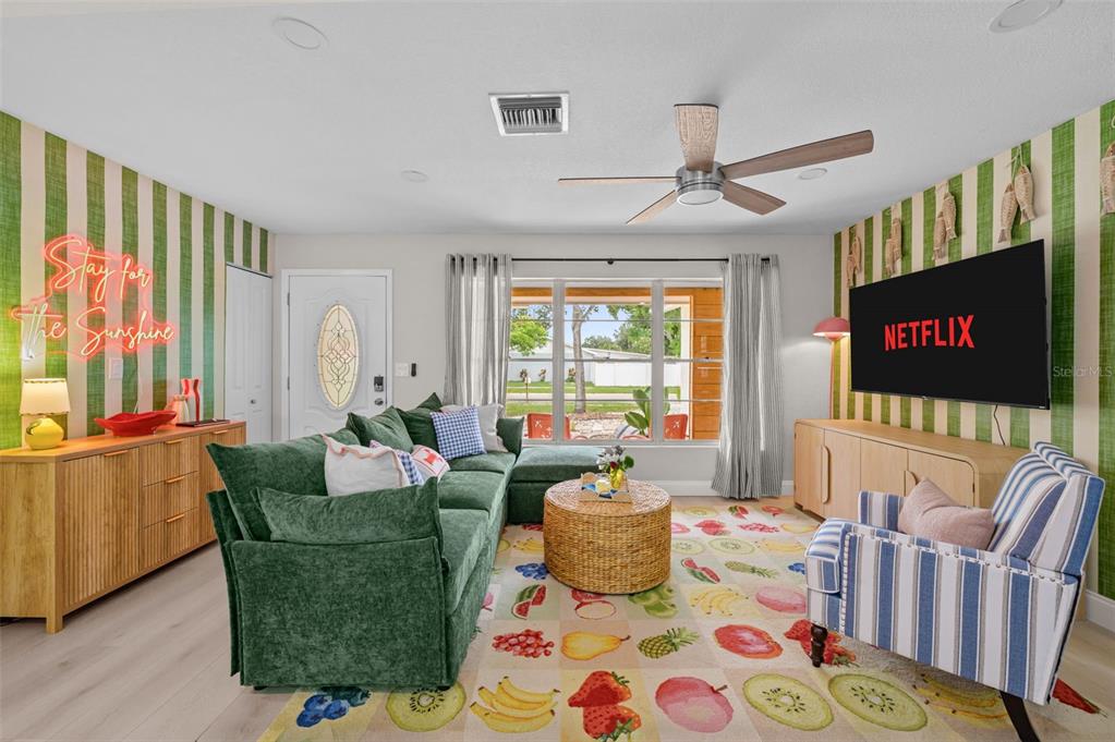 A living room features green striped wallpaper, a green sectional sofa, and a fruit-patterned rug — 7957 COTTONWOODE DRIVE, LARGO, FL