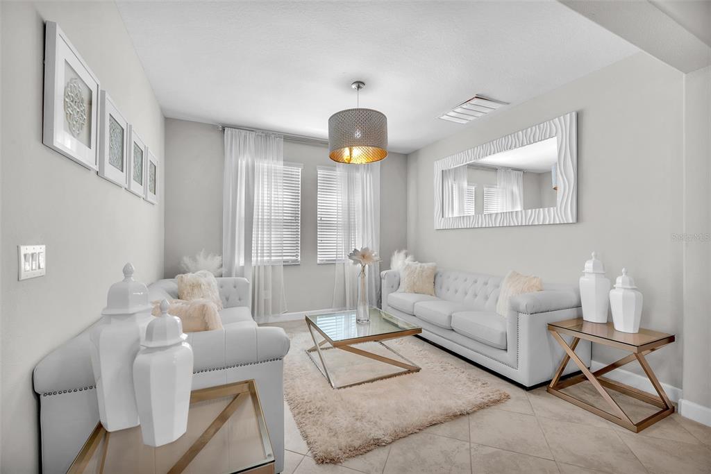 A living room features two white tufted sofas, a glass coffee table, and a large mirror — 13344 ORCA SOUND DRIVE, RIVERVIEW, FL