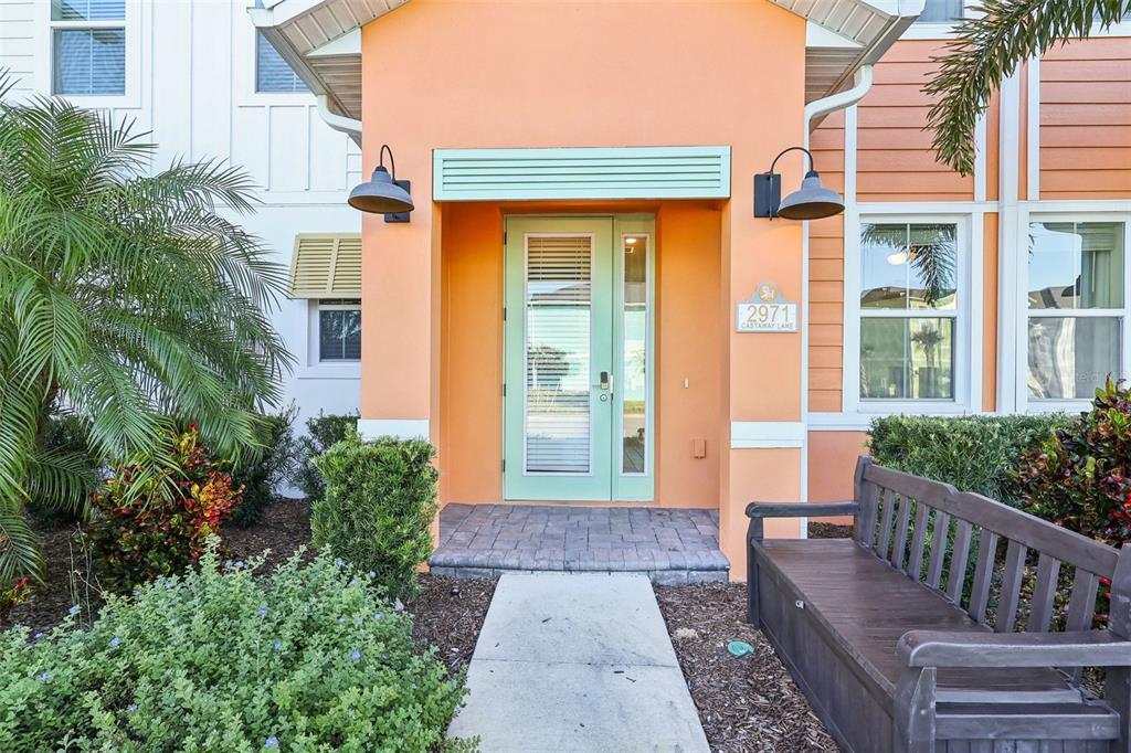 The exterior of a house features a light green front door, orange siding, and landscaping — 2971 CASTAWAY LANE, KISSIMMEE, FL
