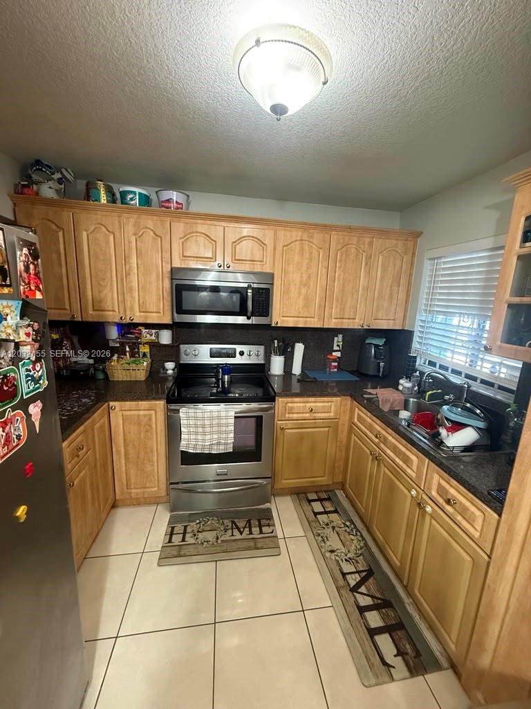 A kitchen features light wood cabinets, stainless steel appliances, and dark countertops — 6081 W 24th Ave # 102, Hialeah FL 33016, HIALEAH, FL