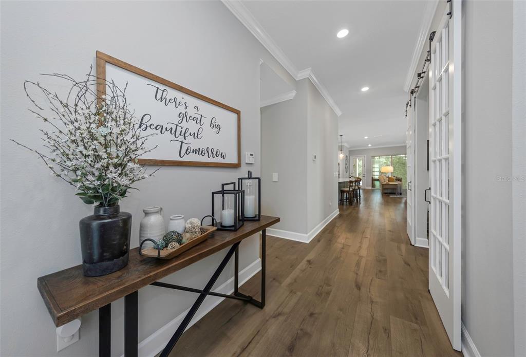A hallway features wood floors, a console table with decor, and a sliding glass door — 13931 NATURES RESERVE DRIVE, LITHIA, FL