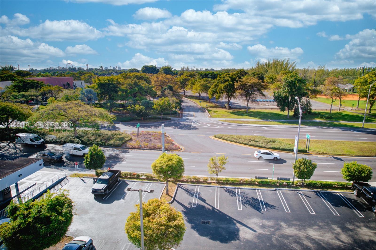 An elevated view shows a parking lot, a multi-lane road, and a park with trees — MIAMI, FL