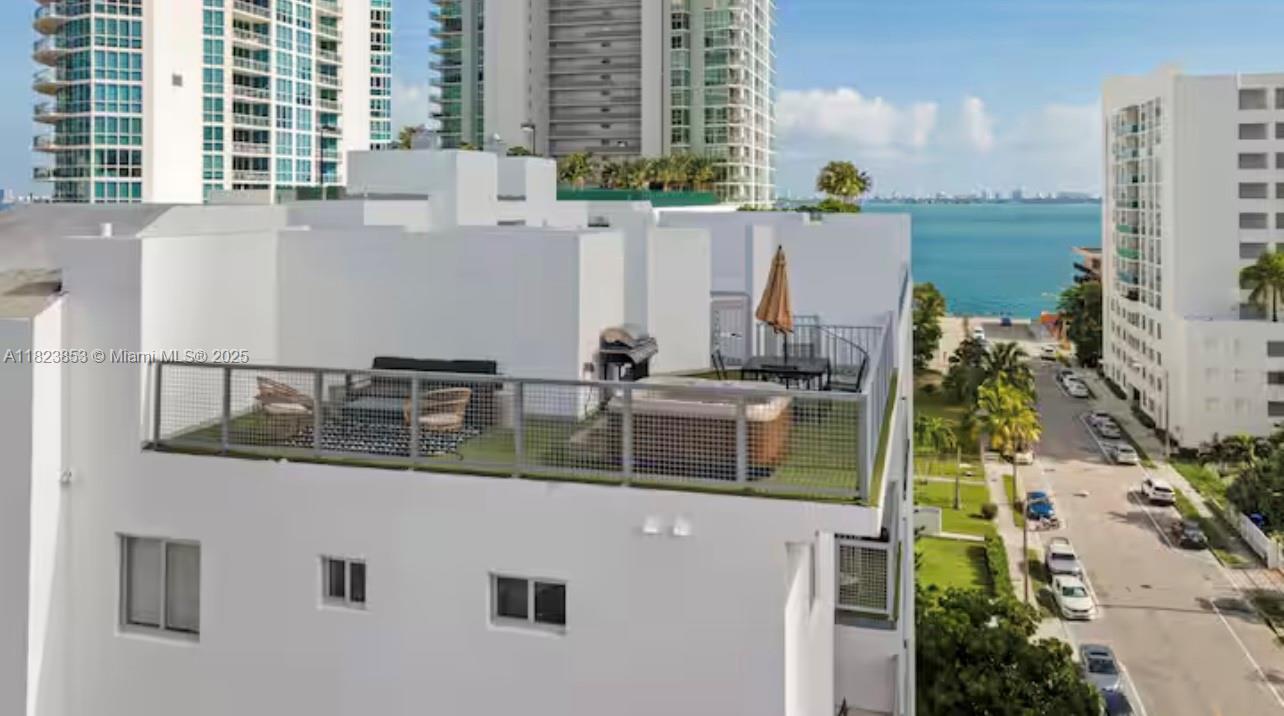 An elevated rooftop terrace features a hot tub, outdoor seating, and a grill overlooking water — 481 NE 29th St # 706, Miami FL 33137, MIAMI, FL