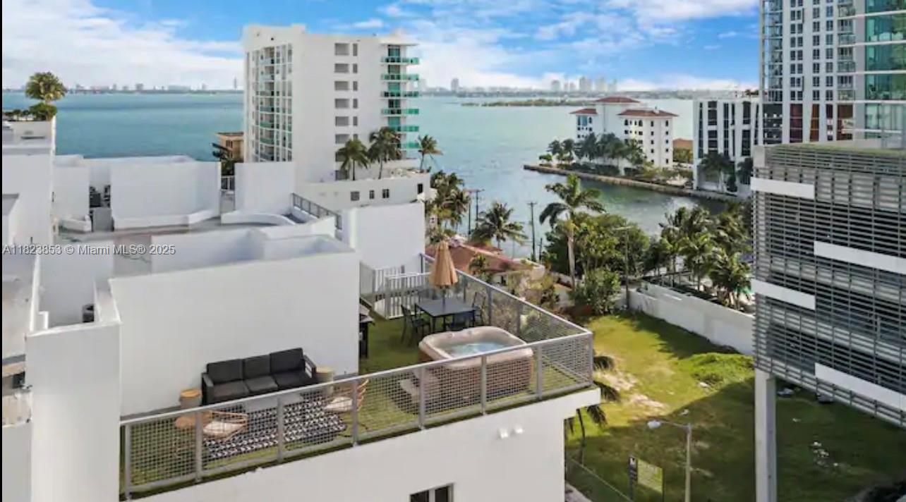 An elevated view of a rooftop terrace featuring a hot tub, seating area, and water views — 481 NE 29th St # 706, Miami FL 33137, MIAMI, FL