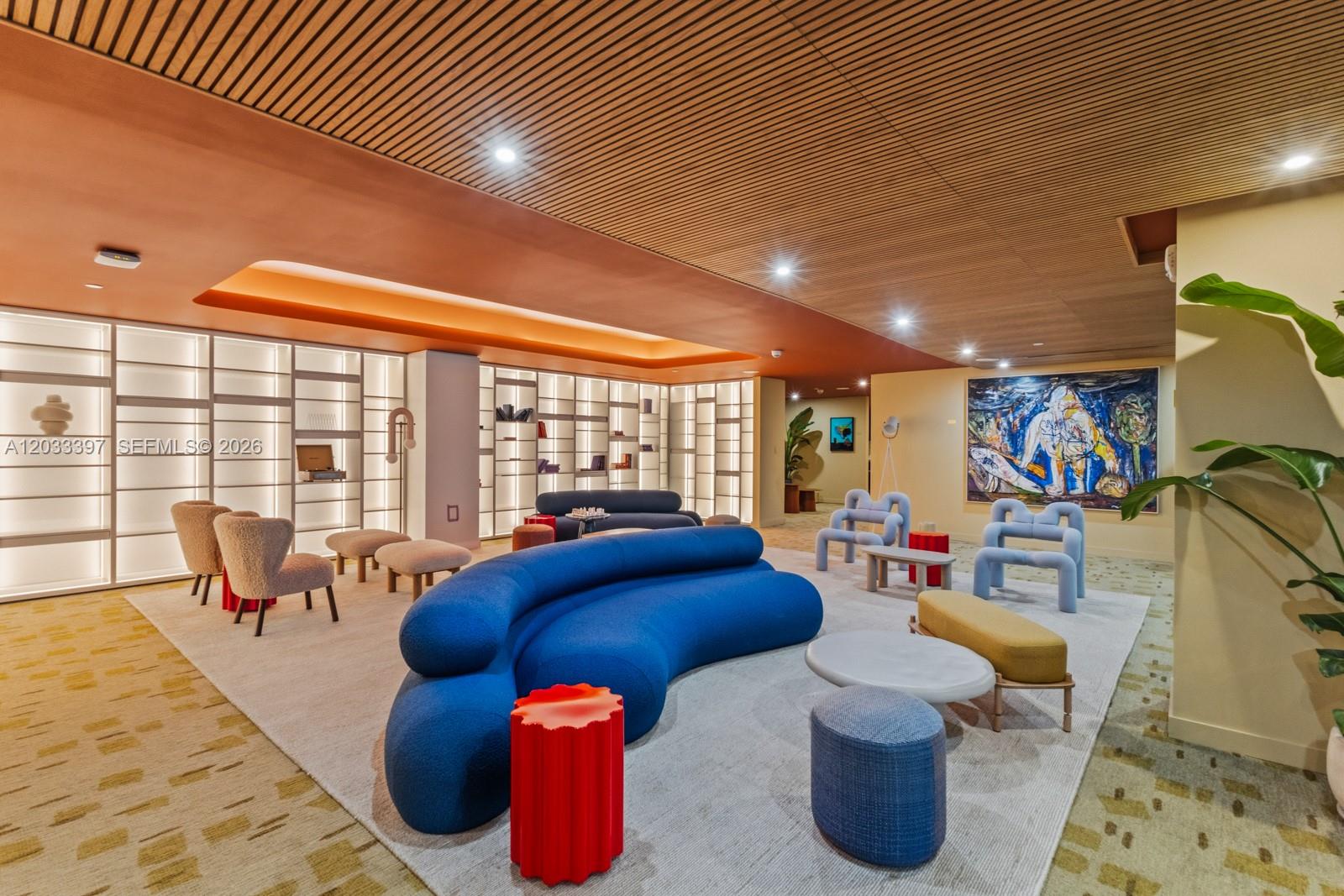 A modern lounge area features a large blue curved sofa, accent furniture, and illuminated shelving — 90 NE 32ND ST # 923, Miami FL 33137, MIAMI, FL