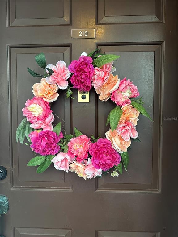 A floral wreath hangs on a dark brown door labeled with the number 210 — 118 S HALIFAX AVENUE UNIT 210, DAYTONA BEACH, FL