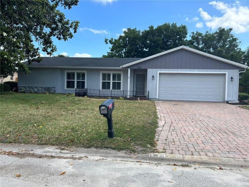 A single-story house with gray siding, a brick driveway, and a two-car garage — 105 E COTTESMORE CIRCLE, LONGWOOD, FL