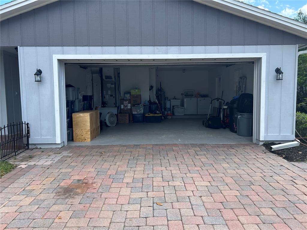 A view of a two-car garage with a paver driveway and gray vertical siding — 105 E COTTESMORE CIRCLE, LONGWOOD, FL