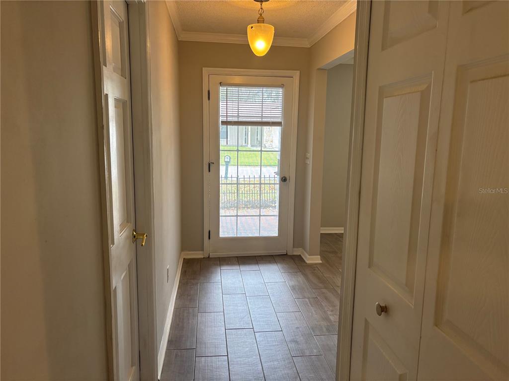 A hallway with wood-look tile flooring leads to a glass-paneled exterior door — 105 E COTTESMORE CIRCLE, LONGWOOD, FL