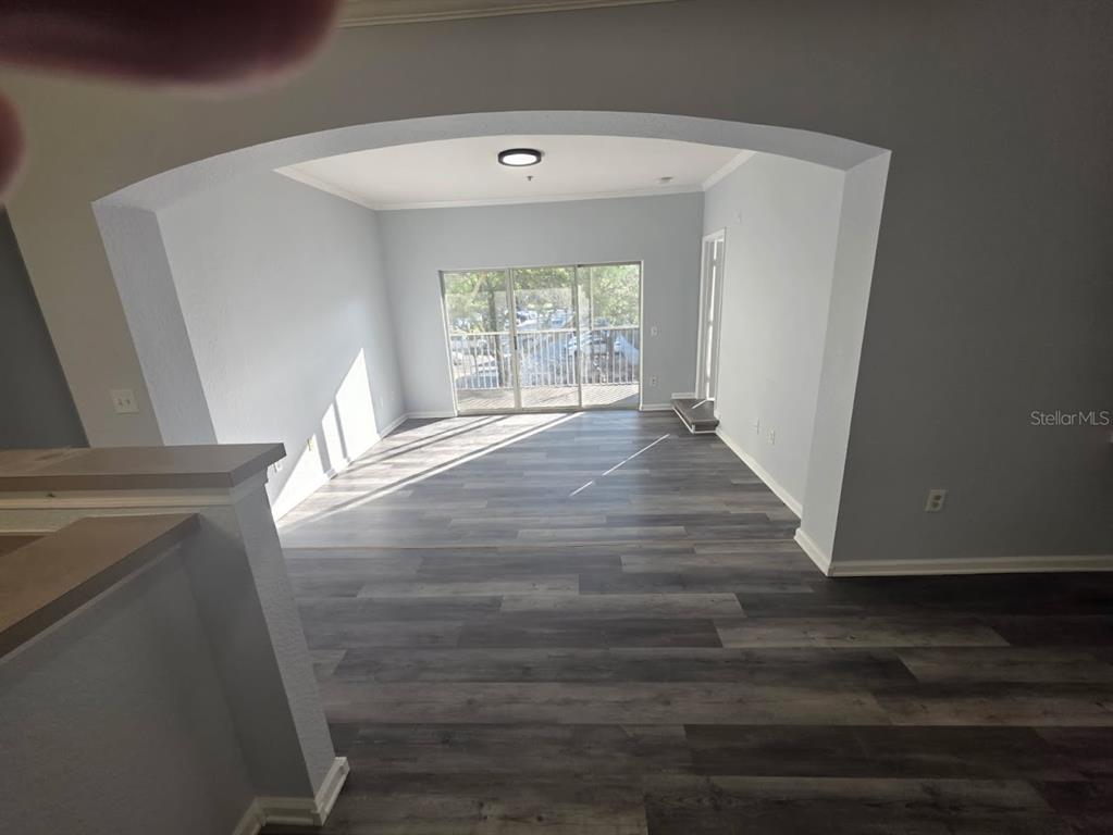 An interior view of a living area with gray wood-look flooring and a sliding glass door — 9401 CRESCENT LOOP CIRCLE UNIT 203, TAMPA, FL