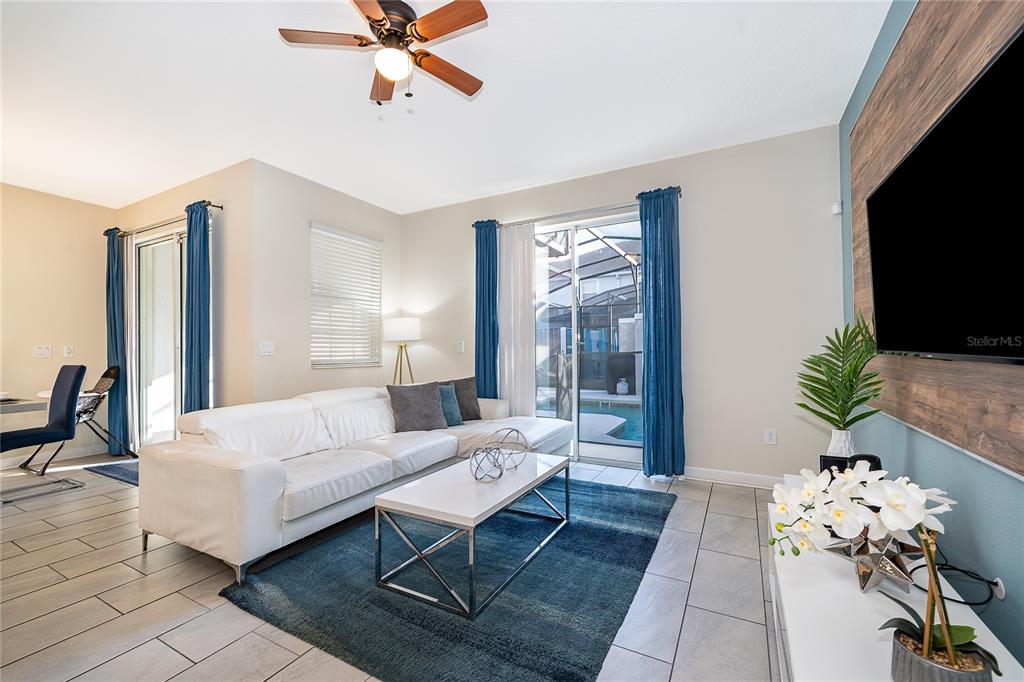 An open-concept dining area and kitchen feature blue chairs, a wood-paneled wall, and tile flooring — 4982 WINDERMERE AVENUE, KISSIMMEE, FL