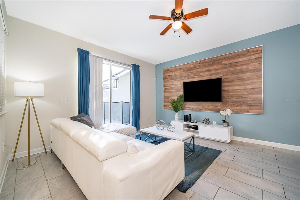 A living room features a white sectional sofa, a blue area rug, and sliding glass doors — 4982 WINDERMERE AVENUE, KISSIMMEE, FL