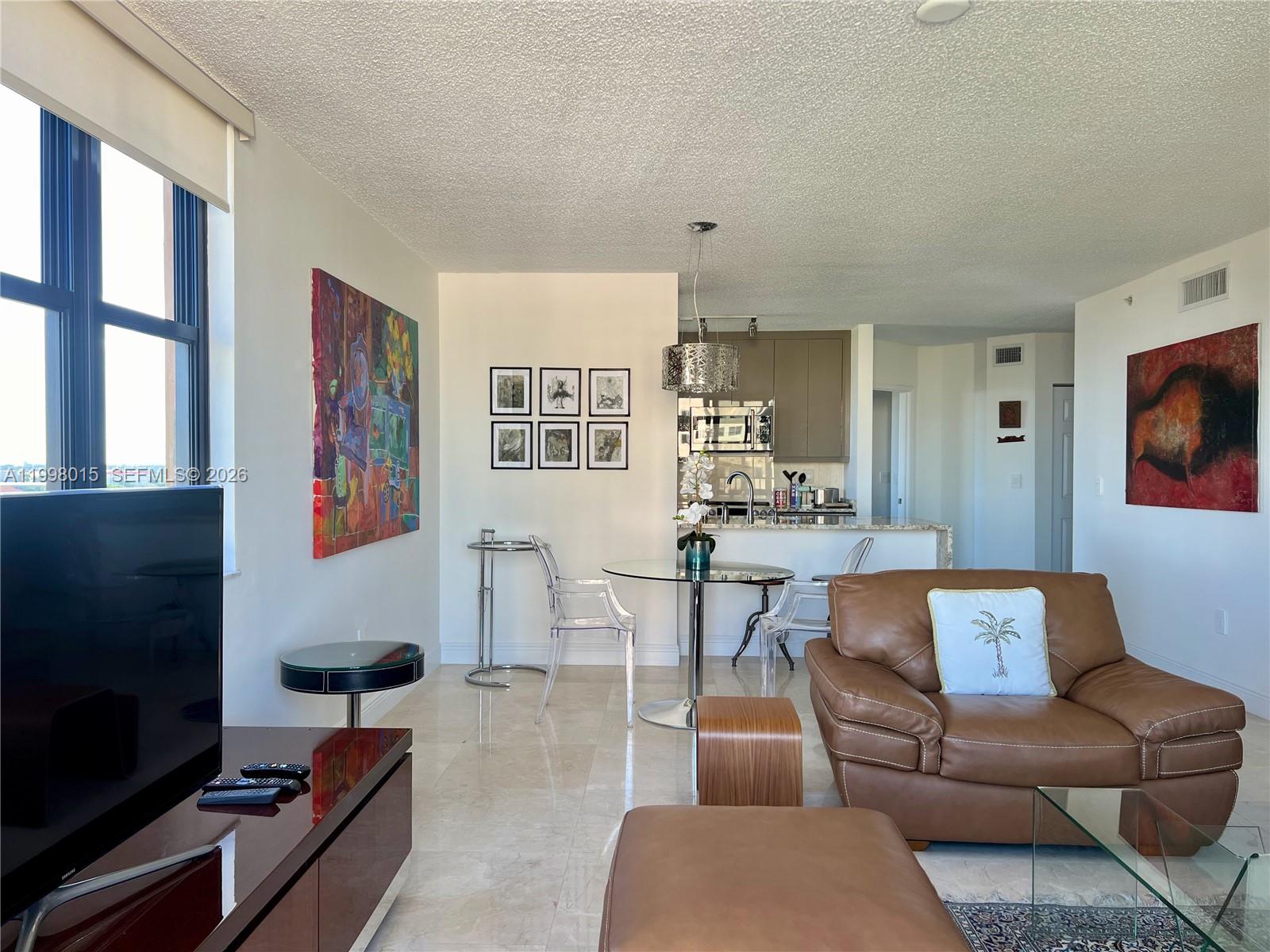 A living room and dining area feature light tile floors, modern furniture, and colorful artwork — 651 Okeechobee Blvd # 811, West Palm Beach FL 33401, WEST PALM BEACH, FL