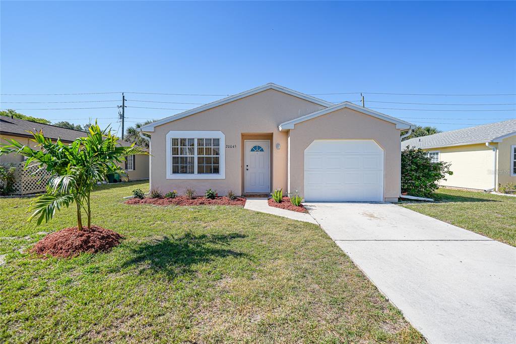 A single-story house with a beige exterior, a white garage door, and a front lawn — 20045 SANCRAFT AVENUE, PORT CHARLOTTE, FL