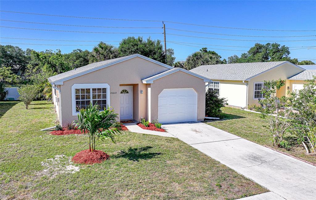 A single-story tan house with a white garage door and a concrete driveway — 20045 SANCRAFT AVENUE, PORT CHARLOTTE, FL