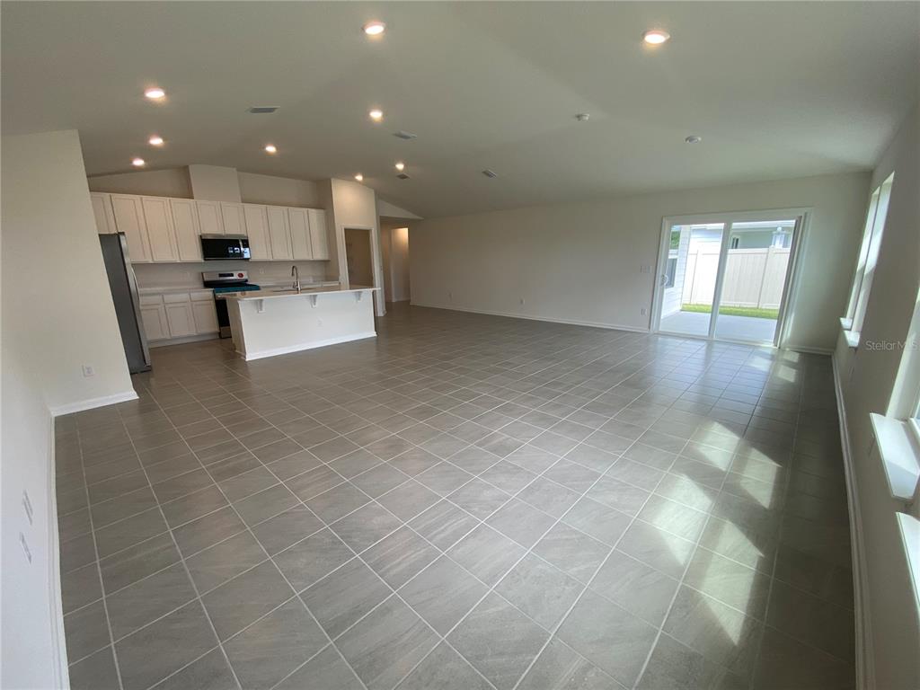 An open-concept kitchen and living area features white cabinets, stainless steel appliances, and tile flooring — 42 CAMELLIA STREET, PALM COAST, FL