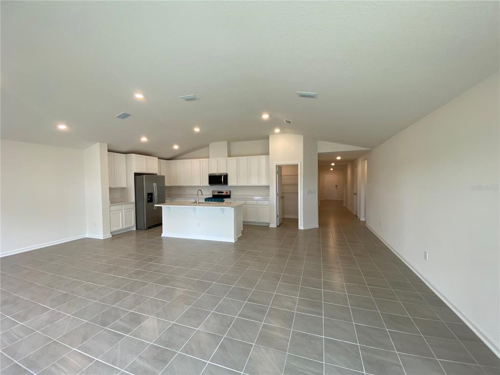 An open-concept kitchen with white cabinets, a central island, and tile flooring — 42 CAMELLIA STREET, PALM COAST, FL