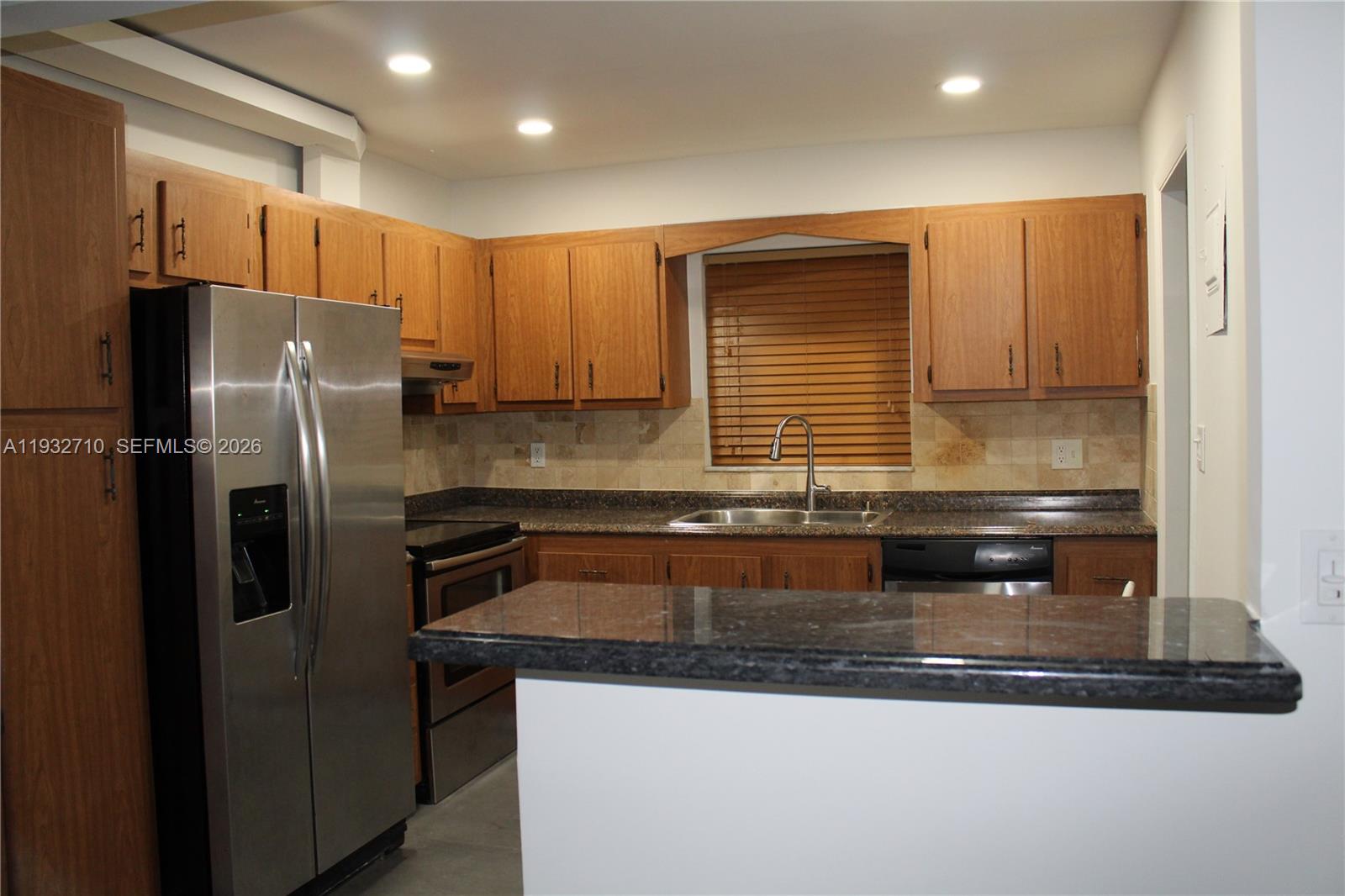 A kitchen features wood cabinets, dark granite countertops, stainless steel appliances, and a breakfast bar — 5140 SW 40th Ave # 3C, Dania Beach FL 33314, DANIA BEACH, FL