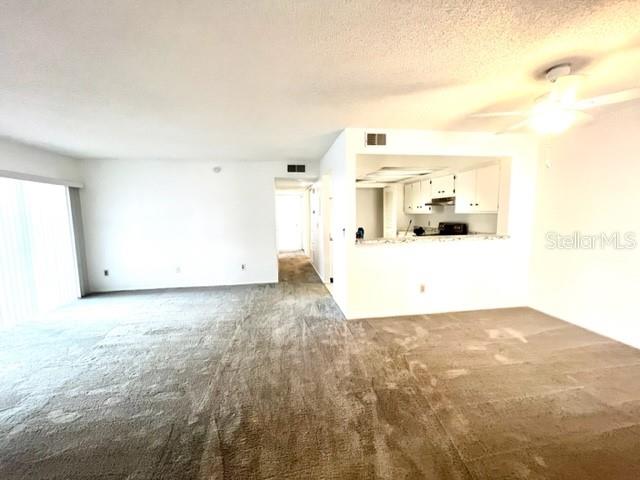 An open-concept living area features beige carpeting and a pass-through kitchen with white cabinets — 2538 CITRUS CLUB LANE UNIT 105, ORLANDO, FL