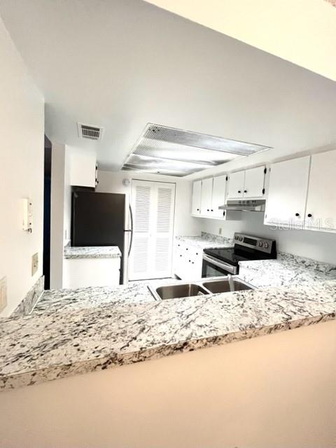 A kitchen features white cabinets, granite countertops, a stainless steel sink, and a black refrigerator — 2538 CITRUS CLUB LANE UNIT 105, ORLANDO, FL