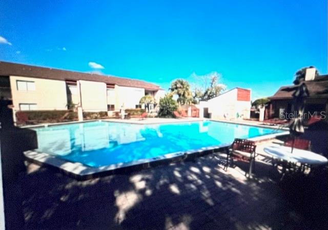 A rectangular swimming pool sits on a paved patio next to a multi-story apartment building — 2538 CITRUS CLUB LANE UNIT 105, ORLANDO, FL