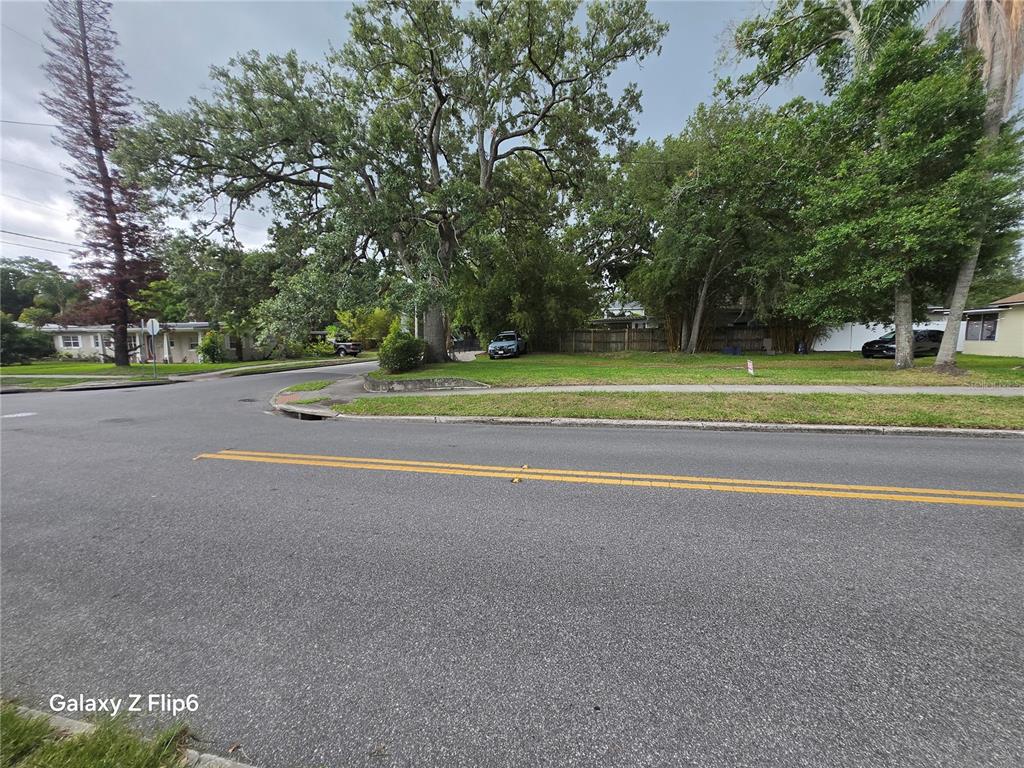 A vacant, grassy corner lot features several large trees and a sidewalk — HELEN AVENUE, ORLANDO, FL