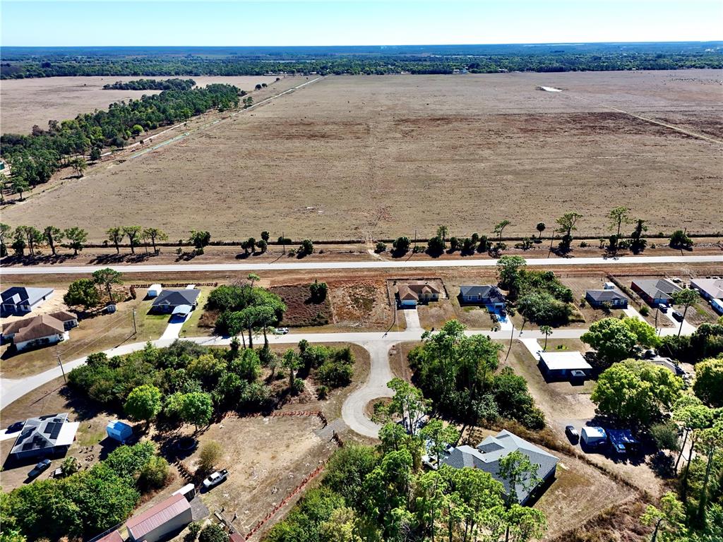 An aerial view shows a residential neighborhood bordering a large, open field — 3019 S BALSAM CIRCLE, LABELLE, FL