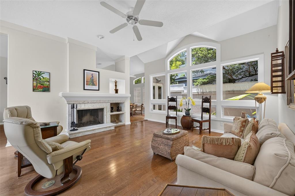 A living room features a fireplace, hardwood floors, a ceiling fan, and large arched windows — 786 MCINTYRE AVENUE, WINTER PARK, FL