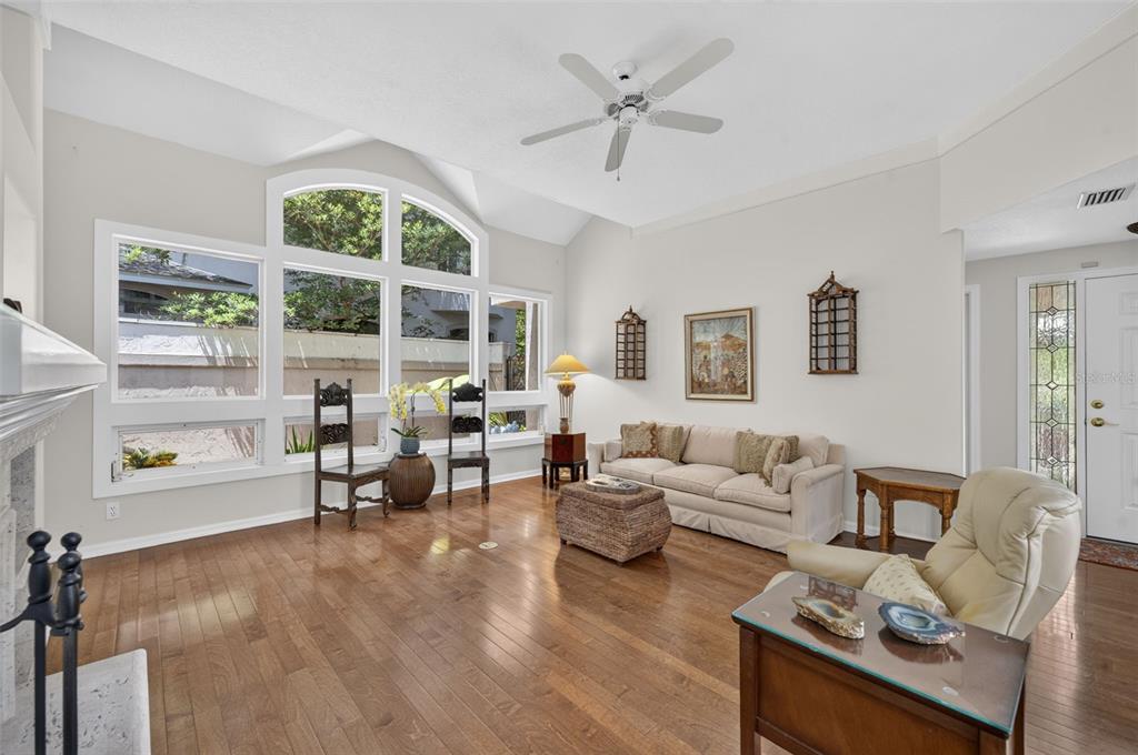 A living room with hardwood floors, a vaulted ceiling, and large windows overlooking a patio — 786 MCINTYRE AVENUE, WINTER PARK, FL