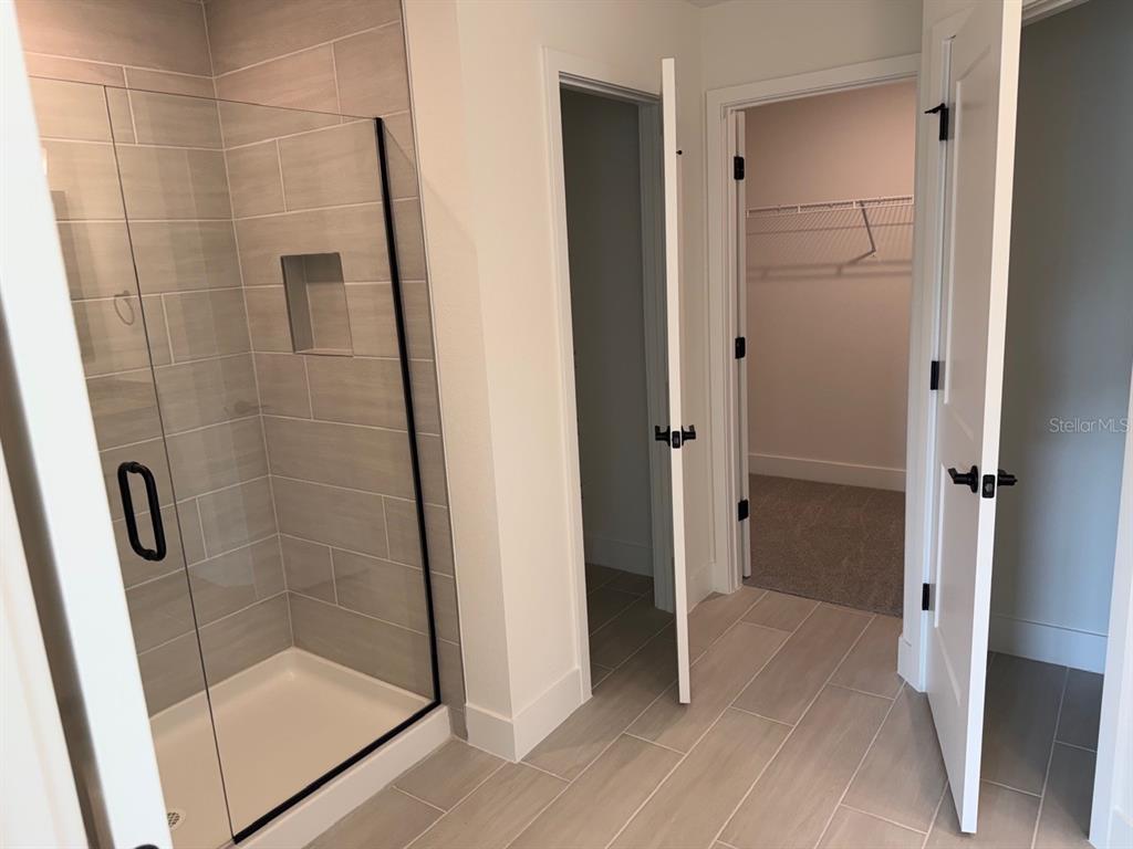 A bathroom features a glass-enclosed shower, a walk-in closet, and light-colored tile flooring — 2110 CARPETGREEN STREET, PORT CHARLOTTE, FL