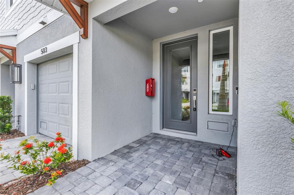 A gray front door and garage entrance with a red fire alarm box on the wall — 1617 SEAHAVEN DRIVE UNIT 504, PUNTA GORDA, FL