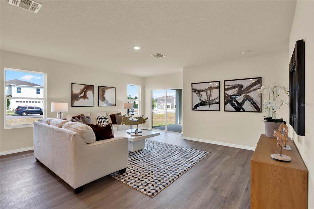 A living room features a light-colored sofa, a geometric rug, and sliding glass patio doors — 7833 FORREST FOX WAY, LAKELAND, FL