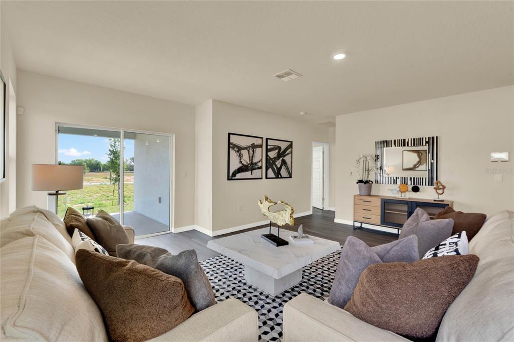 A living room features a white sofa, a marble coffee table, and a sliding glass door — 7833 FORREST FOX WAY, LAKELAND, FL