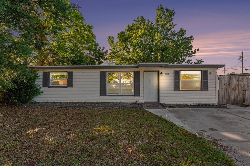 A single-story house with white siding, dark shutters, and a concrete driveway at dusk — 8036 ROSE TERRACE, SEMINOLE, FL