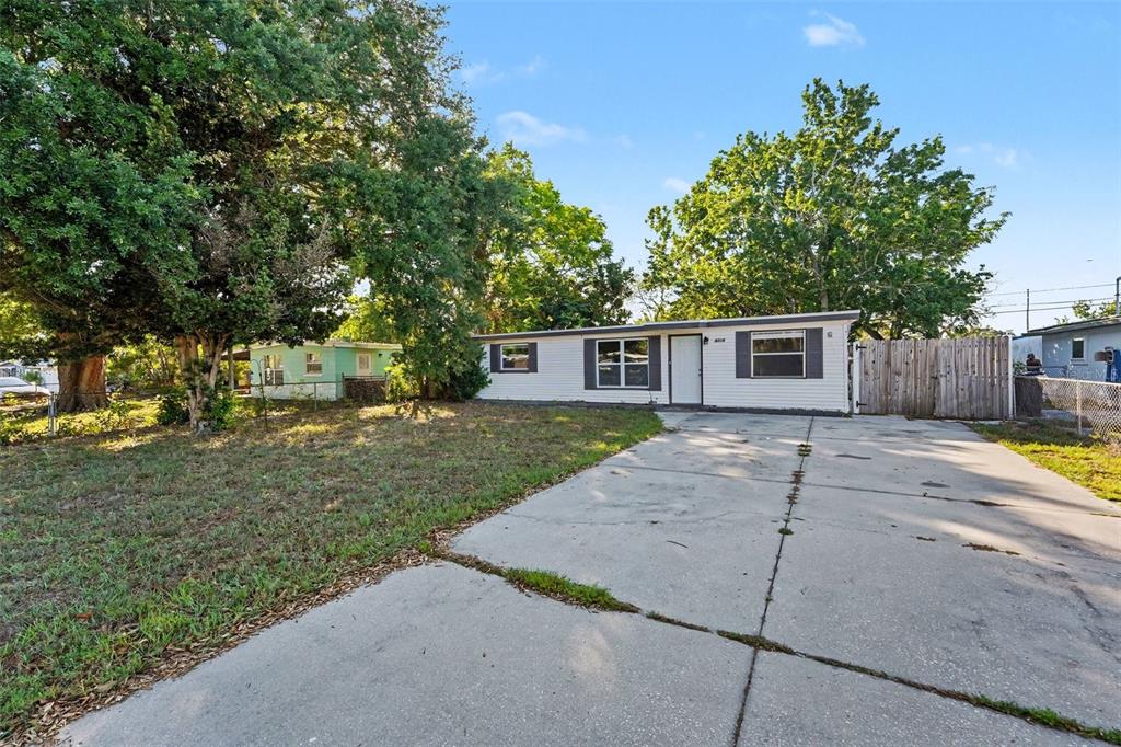 A single-story house with white siding and a concrete driveway sits under large trees — 8036 ROSE TERRACE, SEMINOLE, FL