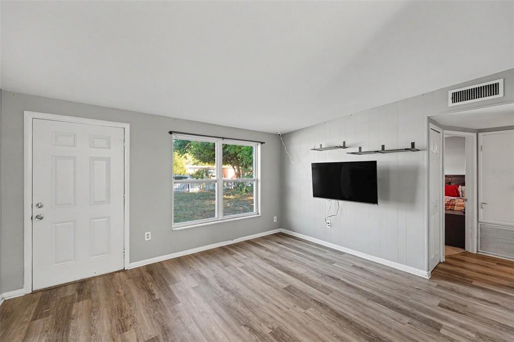 A living room features light gray walls, wood-look flooring, a mounted television, and a window — 8036 ROSE TERRACE, SEMINOLE, FL