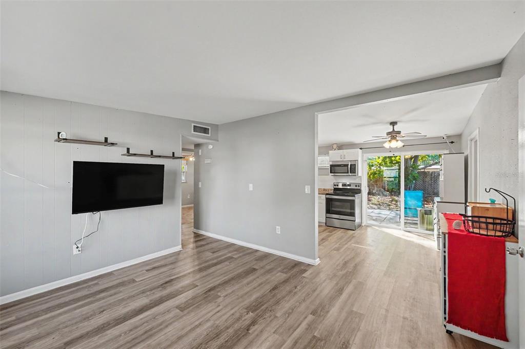A living room with gray walls, wood-look flooring, and a view into the kitchen — 8036 ROSE TERRACE, SEMINOLE, FL