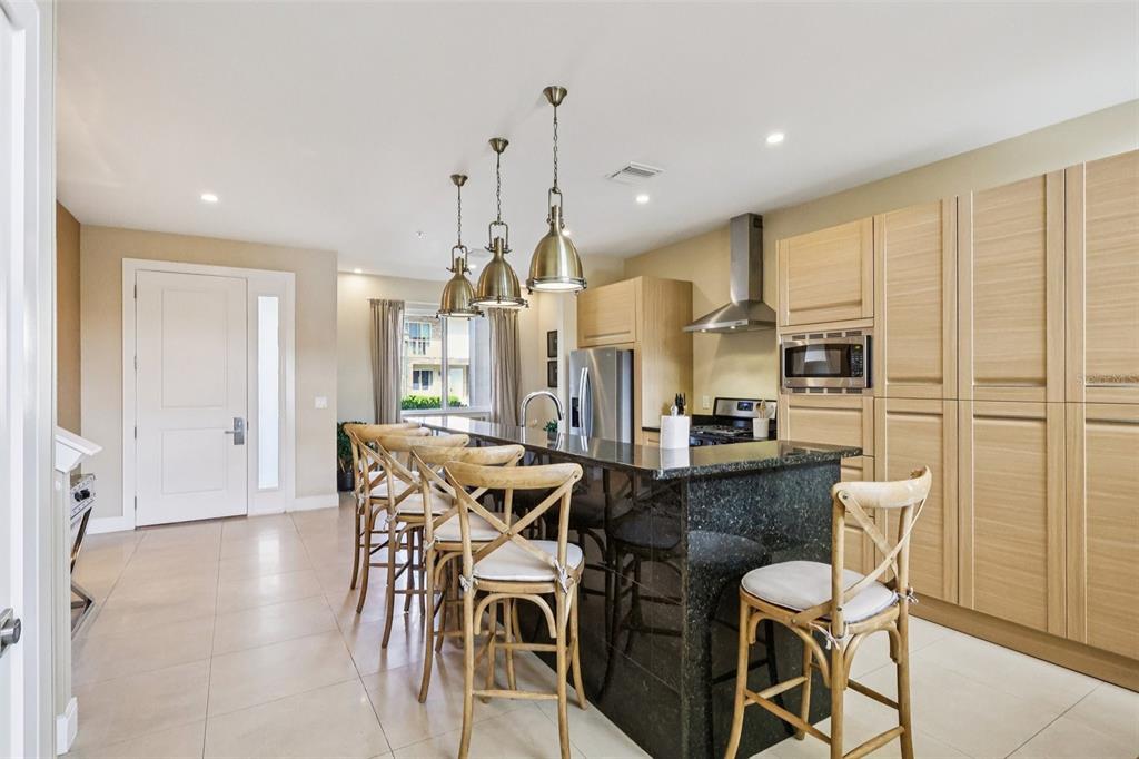 A kitchen features a dark granite island with bar seating and light wood cabinetry — 3191 BRASILIA AVENUE, KISSIMMEE, FL