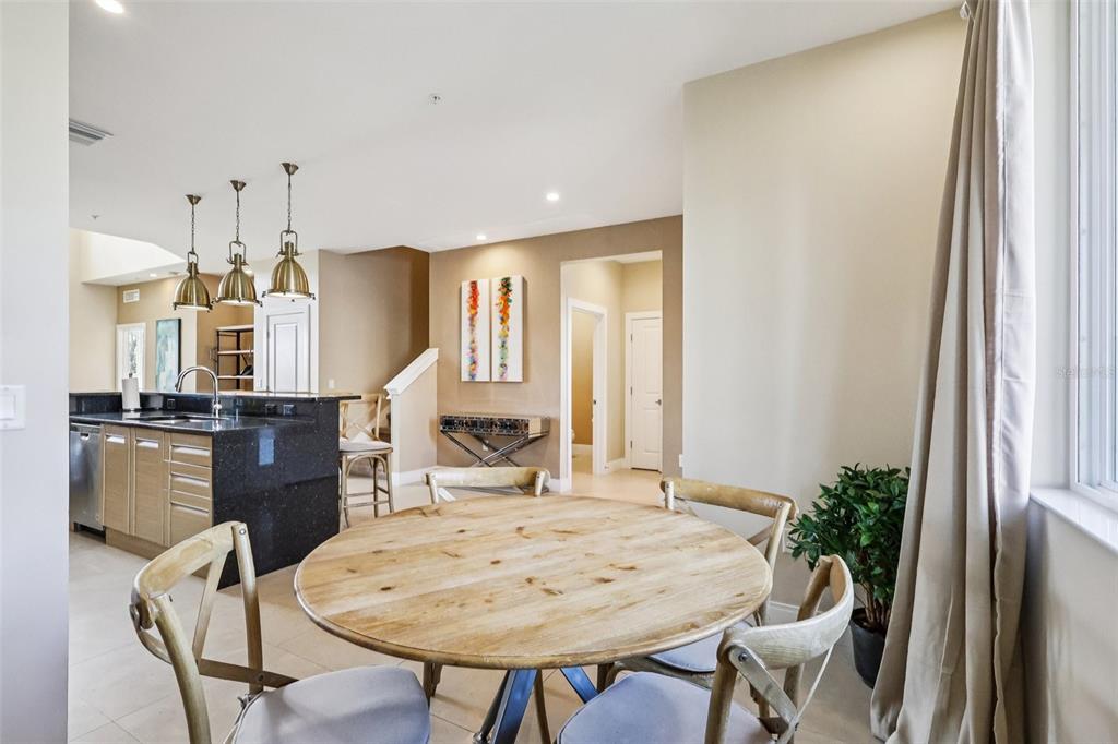 A dining area with a round wooden table sits adjacent to a kitchen with island — 3191 BRASILIA AVENUE, KISSIMMEE, FL