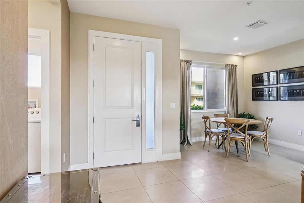A dining area with a round table and chairs sits beside a white entry door — 3191 BRASILIA AVENUE, KISSIMMEE, FL