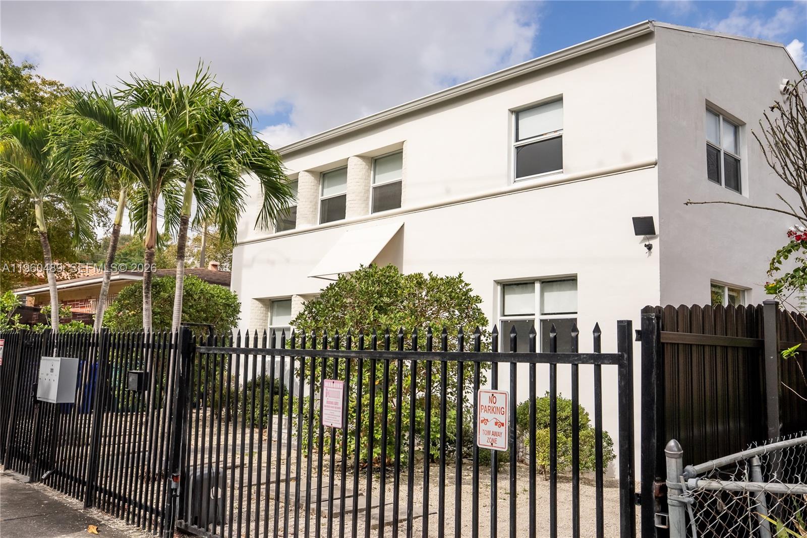 A two-story white building stands behind a black metal fence with palm trees — 509 NE 64th St # 2, Miami FL 33138, MIAMI, FL