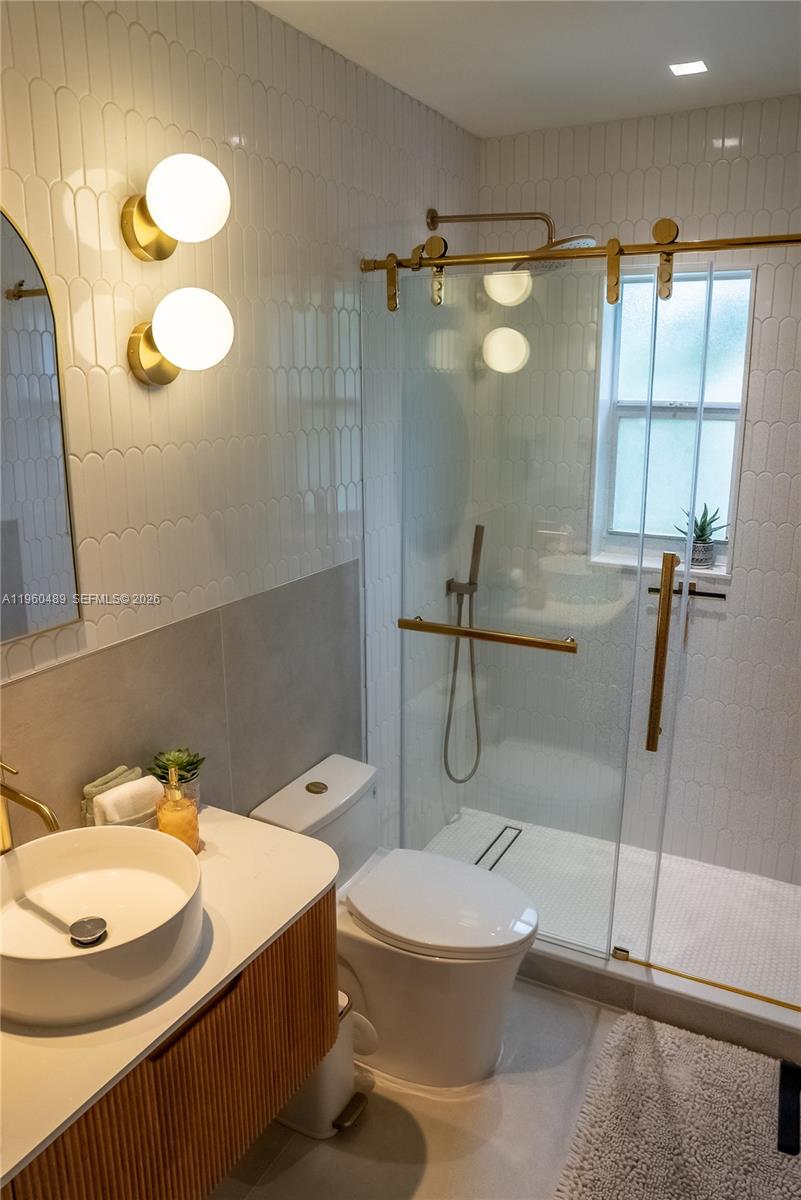 A modern bathroom features a vessel sink, gold fixtures, and a glass-enclosed walk-in shower — 509 NE 64th St # 2, Miami FL 33138, MIAMI, FL