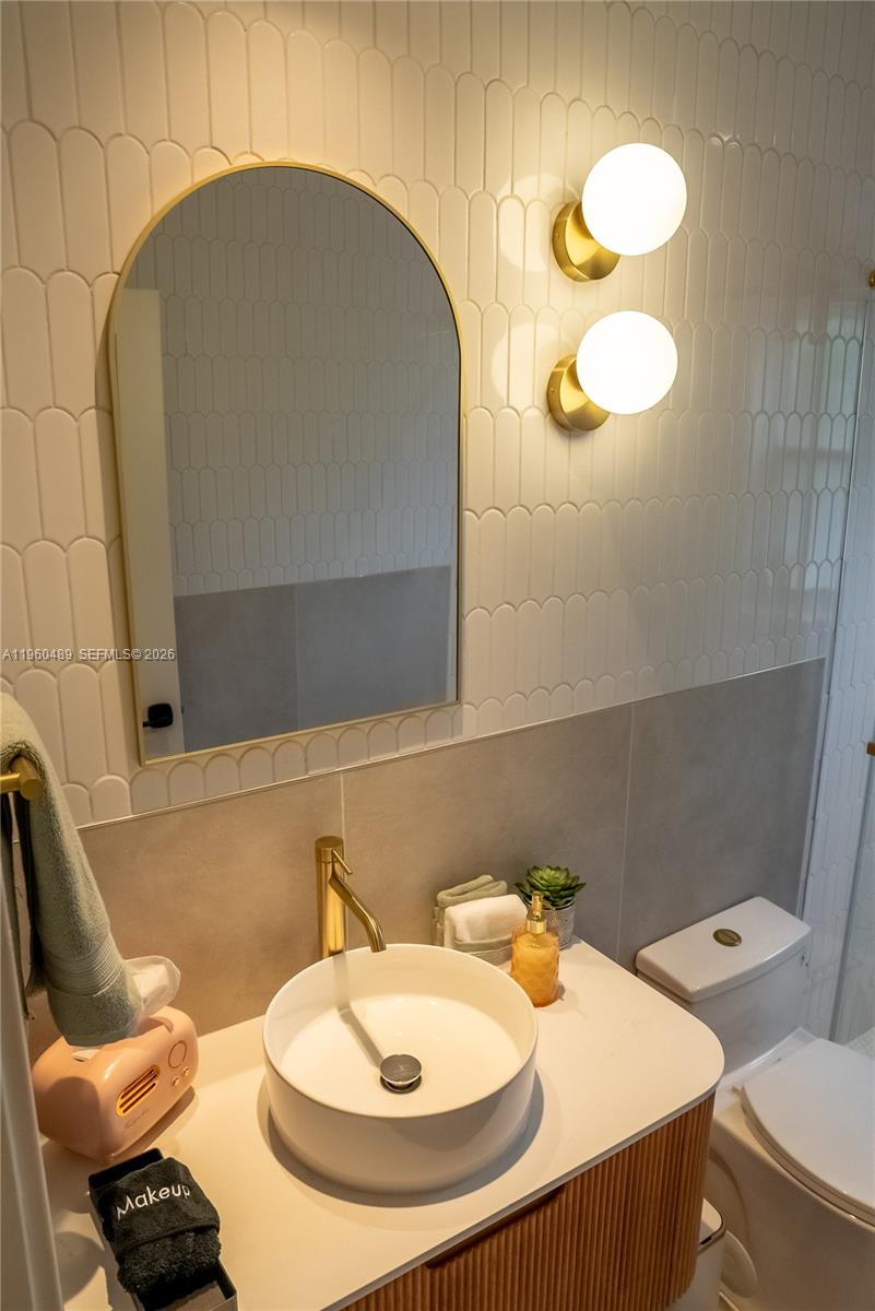 A modern bathroom features a vessel sink, gold faucet, arched mirror, and scalloped wall tiles — 509 NE 64th St # 2, Miami FL 33138, MIAMI, FL