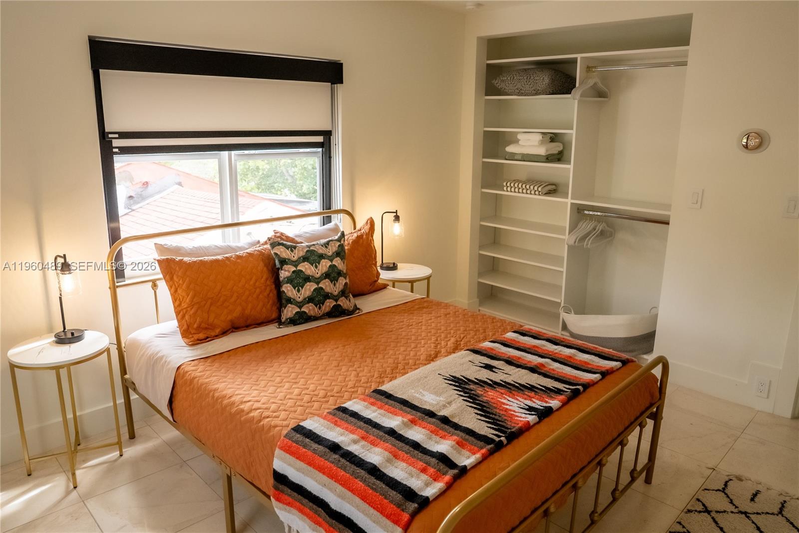 A bedroom features a gold metal bed frame, orange bedding, and an open closet with shelving — 509 NE 64th St # 2, Miami FL 33138, MIAMI, FL