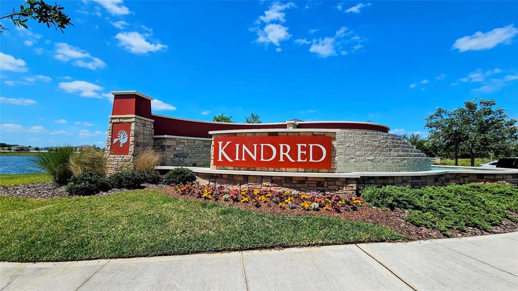 A stone and red monument sign for the Kindred community stands near a pond — 1724 RANGER HIGHLANDS ROAD, KISSIMMEE, FL