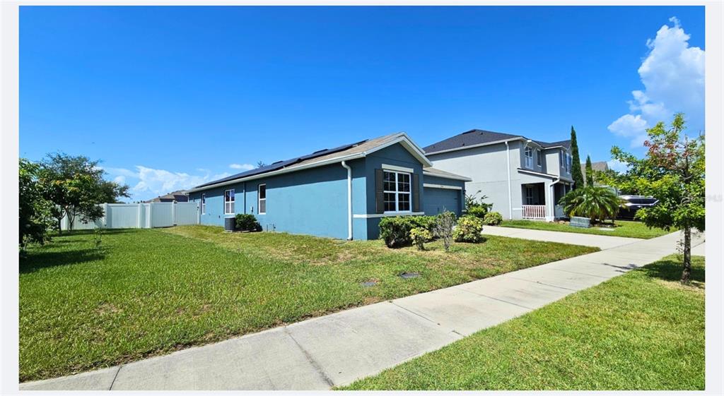 A blue single-story house with solar panels on the roof and a side-entry garage — 1724 RANGER HIGHLANDS ROAD, KISSIMMEE, FL
