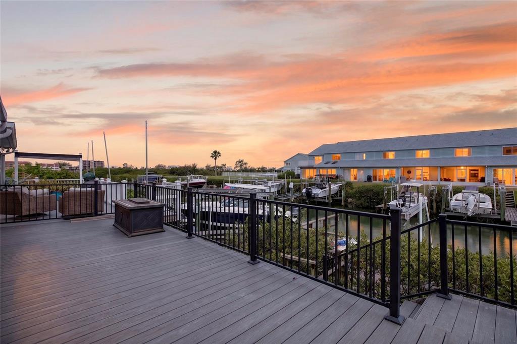 A wooden deck overlooks a canal with docked boats at sunset — 14617 LORIDAWN DRIVE UNIT 8, SEMINOLE, FL